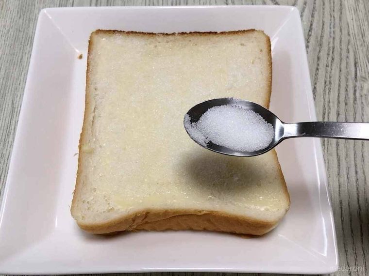 白い角皿にのった食パンにグラニュー糖をまぶす様子