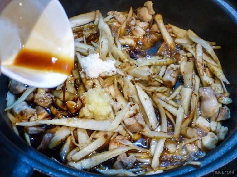 鶏肉とごぼうを炒めたフライパンに調味料を加える様子