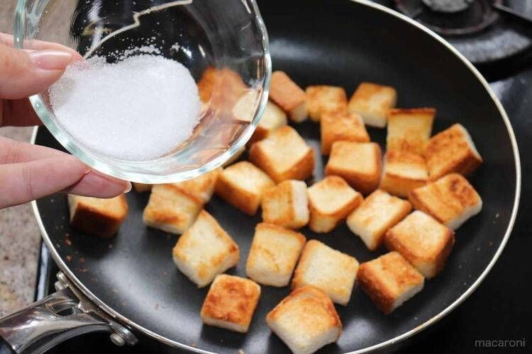 食パンを炒めたフライパンにグラニュー糖を加える様子