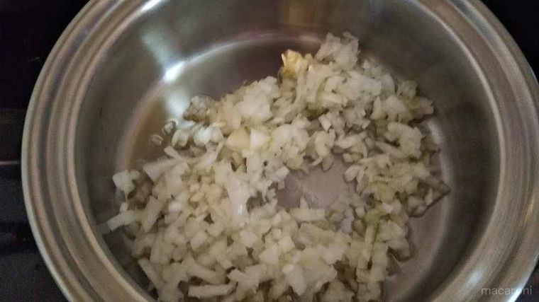 ステンレスの鍋で炒められている、みじん切り玉ねぎのアップ