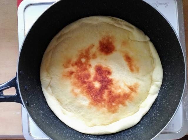 フライパンの中のひっくり返したピザ生地