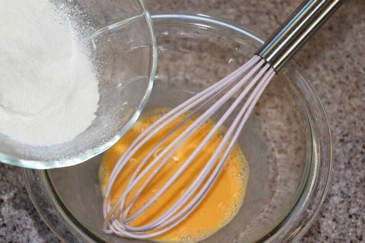 卵液が入ったボウルと泡だて器と振るった粉類
