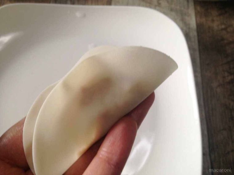餃子の皮を半分に折り、中央を押さえて留めた様子