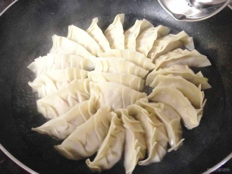 餃子が入ったフライパンを中火にかけて水を加えている様子