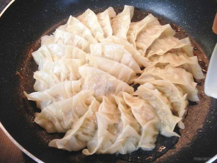 餃子が入ったフライパンにサラダ油を回し入れる様子