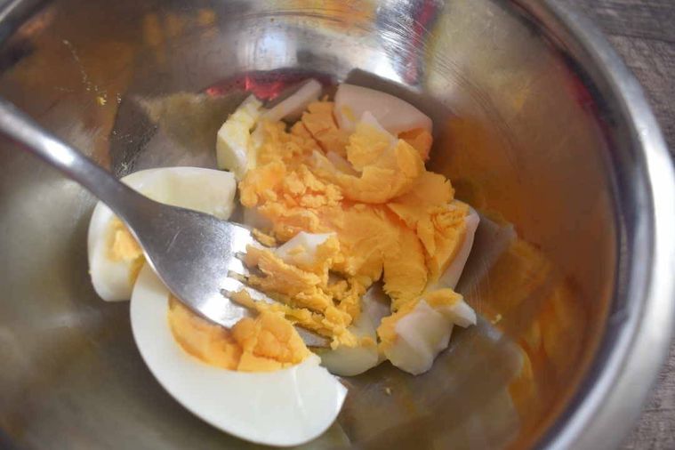 ボウルに入ったゆで卵をフォークでつぶしている様子