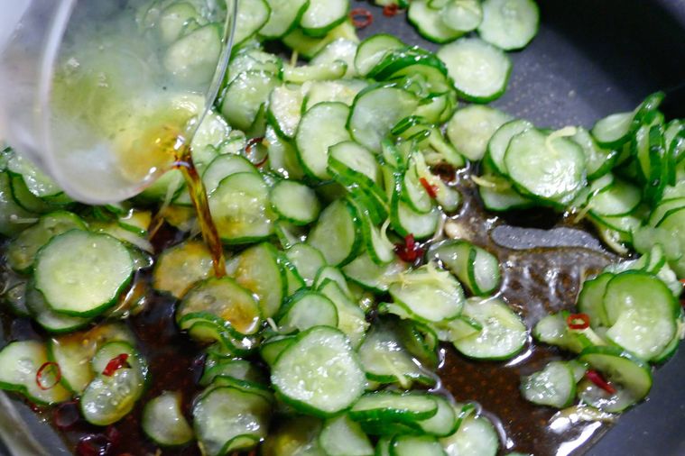 きゅうりが入っているフライパンに調味料を加える様子
