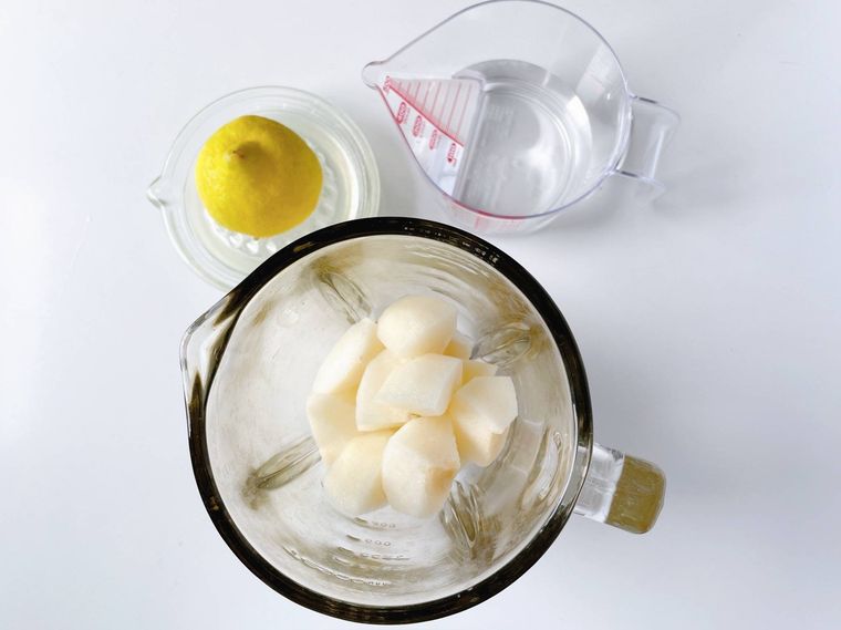 梨が入ったミキサー、レモン果汁、カップに入った水