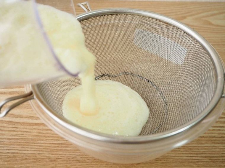 ざるに撹拌したパイナップルを注ぎ入れる様子