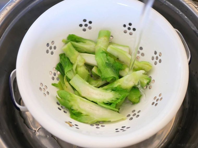 ざるに入ったゆで子持ち高菜に流水をかけている