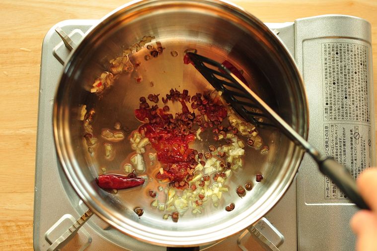 鍋で花椒、豆板醤、赤唐辛子を炒める様子