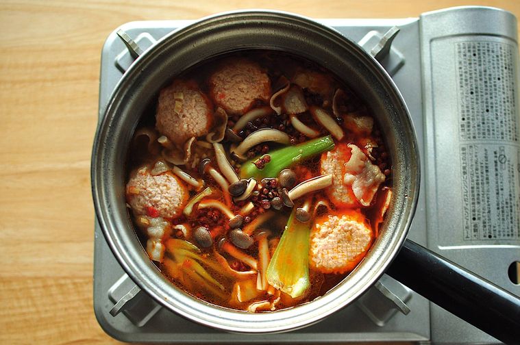 鍋で青梗菜、えび団子、しめじを煮る様子