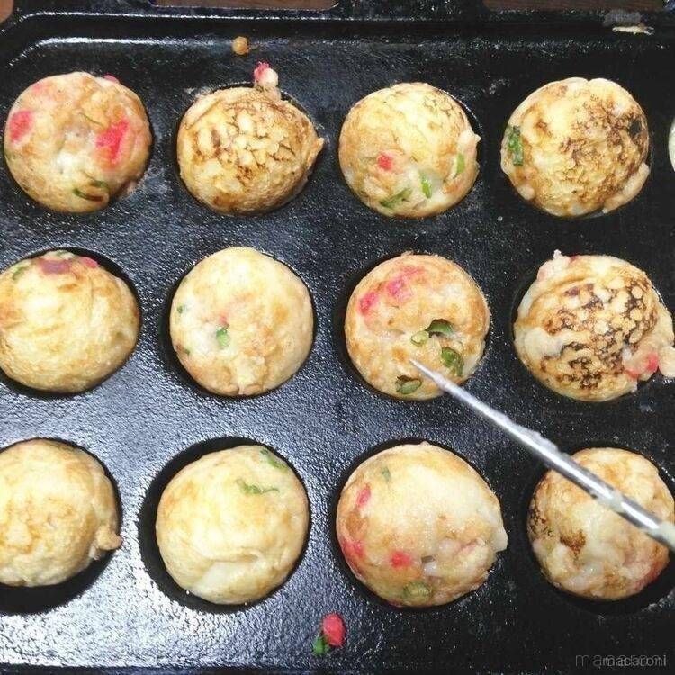 たこ焼きピンで、たこ焼きの形を整えながら焼いている様子