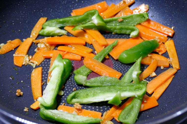にんじんとピーマンを炒める様子