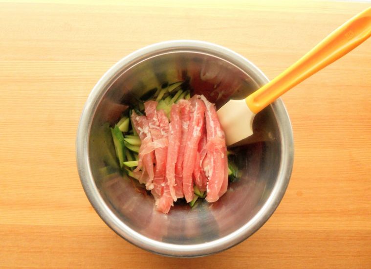 ボウルに生ハムときゅうりを入れ、ゴムベラで和えている様子