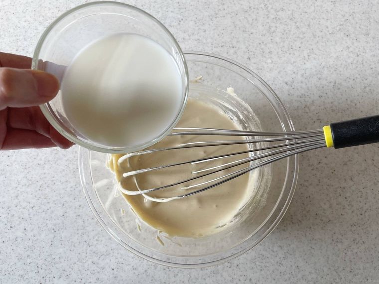 卵黄ときび砂糖を混ぜたボウルに牛乳を加える様子