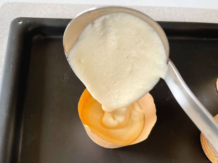 マフィンカップにシフォンケーキ生地をレードルで入れる様子