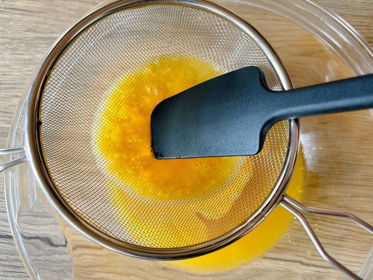 溶き卵をザルで漉す様子