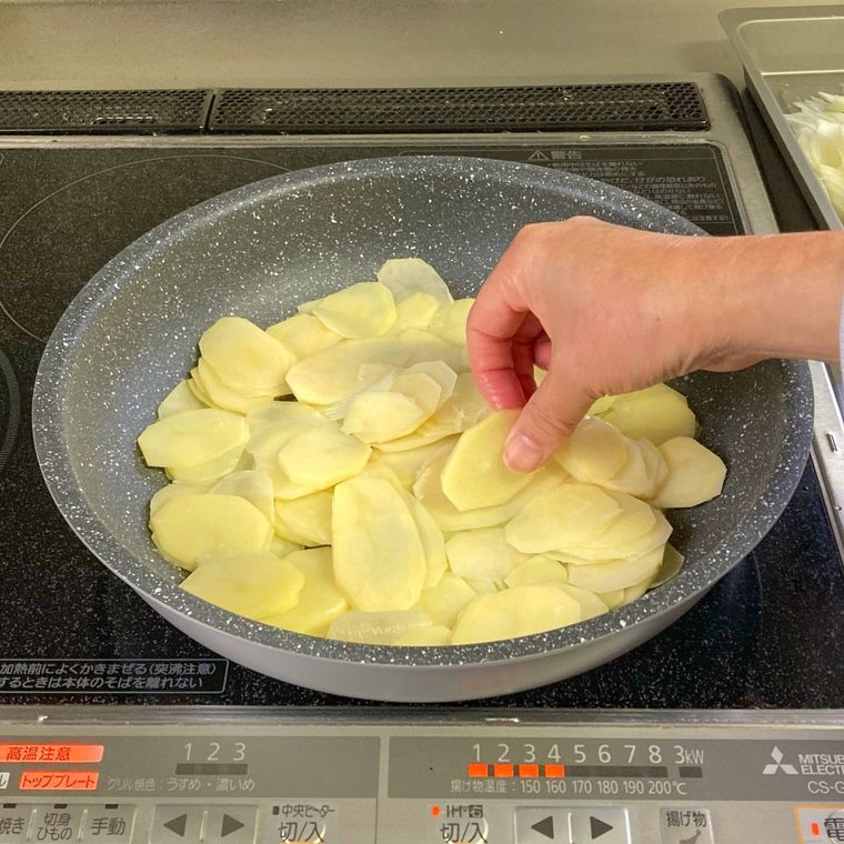薄切りのじゃがいもをフライパンに並べているところ