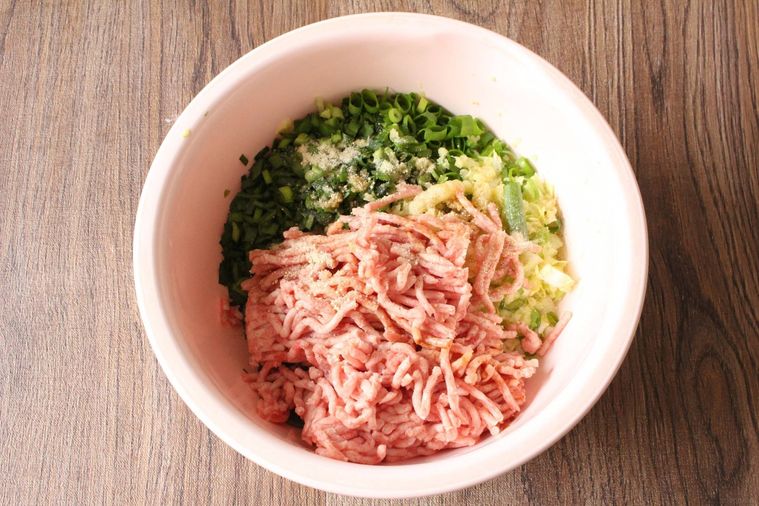 ピンク色のボウルに豚ひき肉やキャベツ、ニラなどが入っている様子