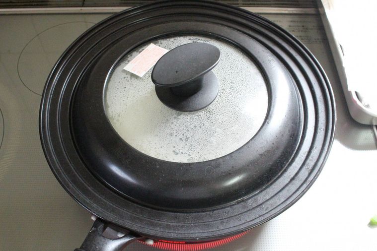 フライパンにフタをして餃子を蒸らしている様子