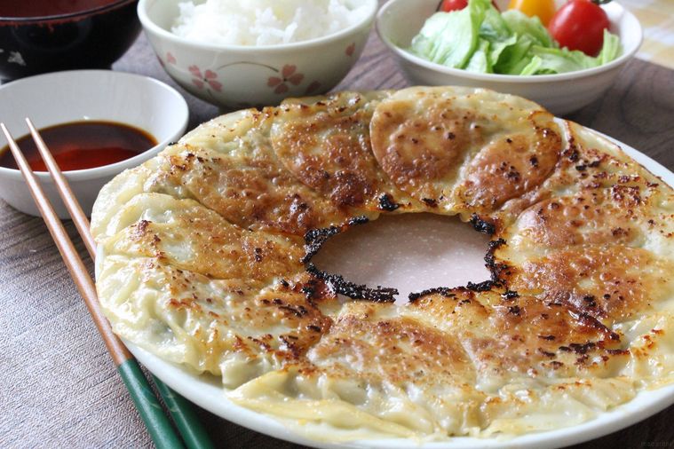 大皿に盛られた餃子とごはんやサラダが添えられている様子