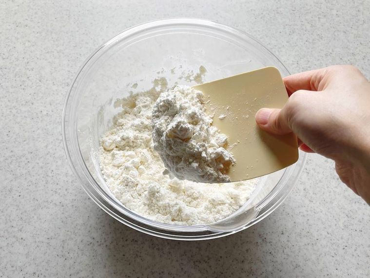 ボウルの中で粉とバターを切り混ぜたものをすくっている