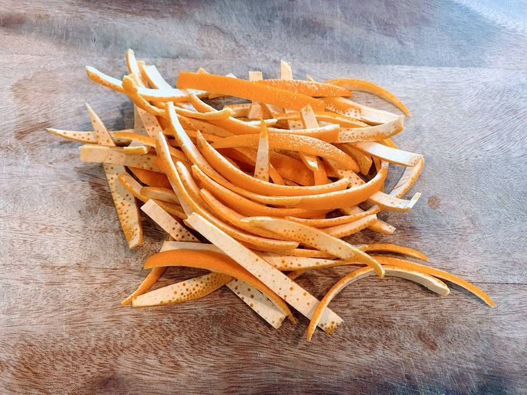 細切りにしたオレンジピールが木のテーブルにのっている様子