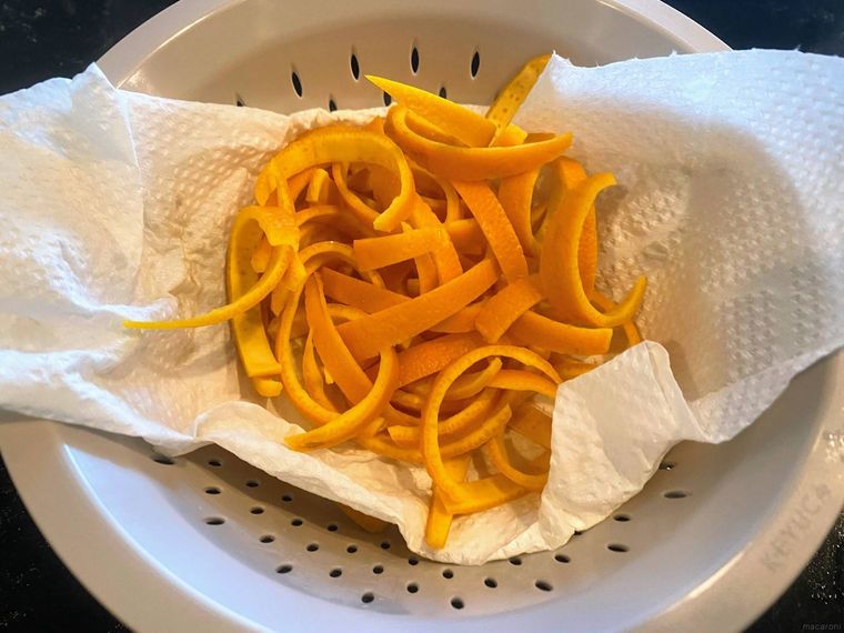 クッキングペーパーを敷いたザルに入ったオレンジピール