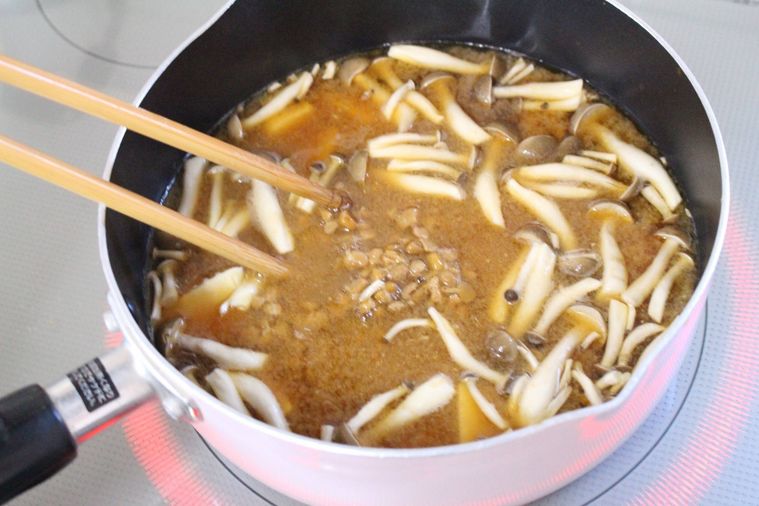 きのこと絹豆腐の入ったみそ汁に納豆を入れている様子