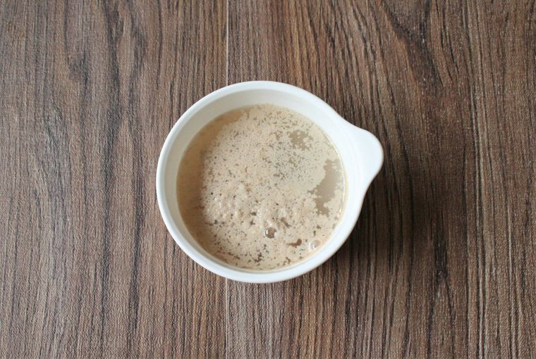 白い器にドライイーストを入れてぬるま湯で溶かしている様子