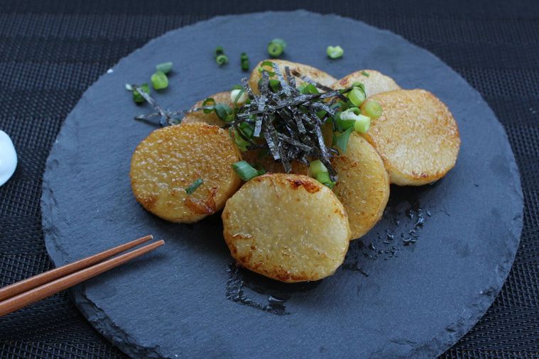 黒いお皿に万能ねぎと海苔をトッピングされた山芋ステーキが盛られ、箸が添えられている様子
