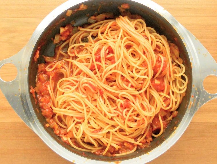トマトソースとゆでたパスタを和えているフライパン