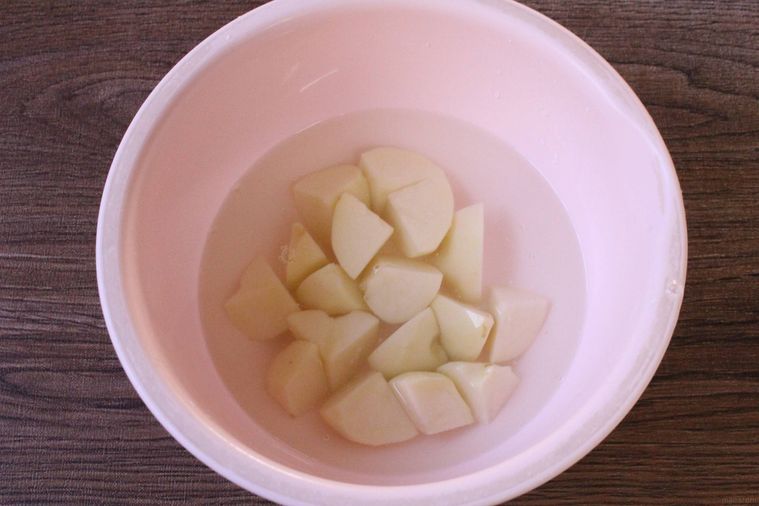 ピンク色のボウルにじゃがいもを入れ水にさらしている