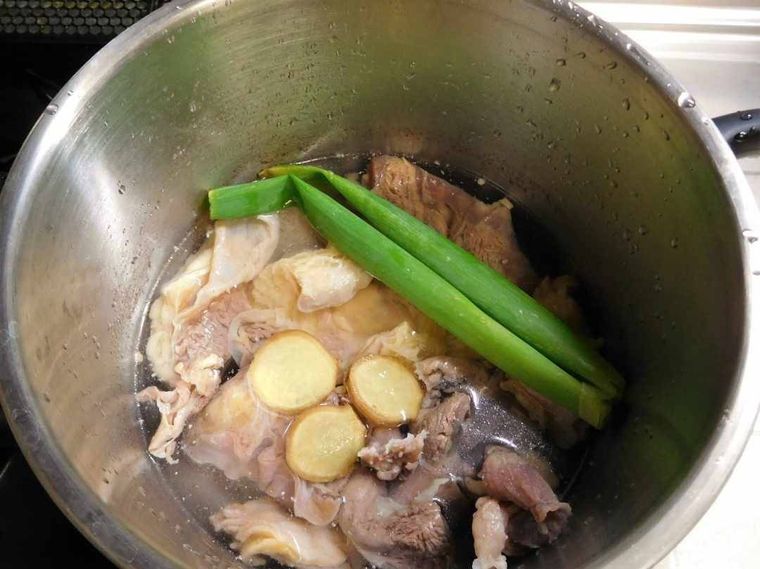 圧力鍋の中に入った牛すじ肉とネギ