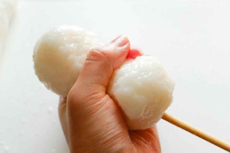 割りばしに刺したごはんを握るように形をととのえる様子