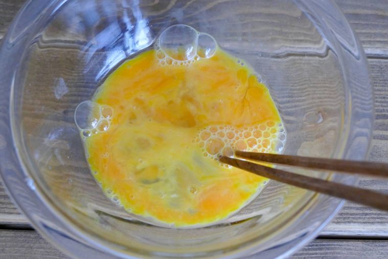 ボウルに入っている卵を箸でほぐす様子