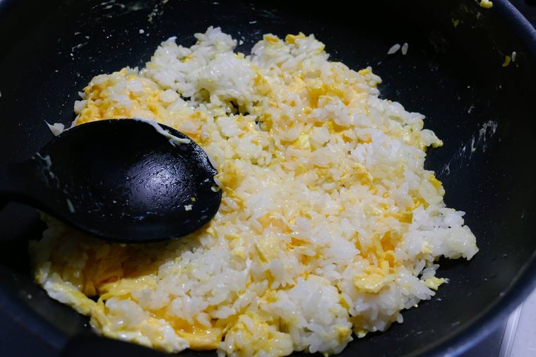 フライパンにごはんを入れてお玉で押さえながら炒める様子