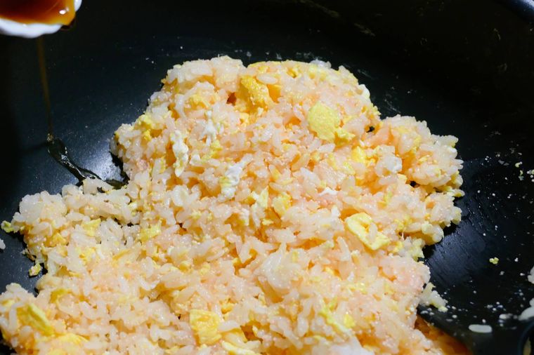 たらこチャーハンが入っているフライパンの鍋肌からしょうゆを加える様子