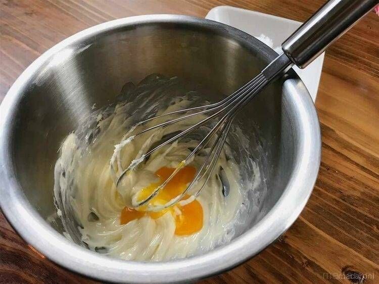 ボウルの中で泡立て器を使ってバターと卵黄を混ぜている様子