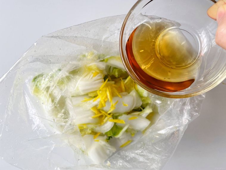 ポリ袋に入った白菜に、白だしを入れる様子