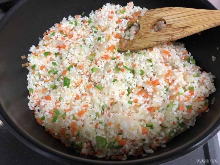 野菜にお米を加えて炒めている様子