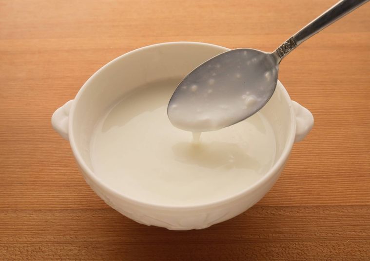 白い器に入ったヨーグルトをスプーンですくう様子