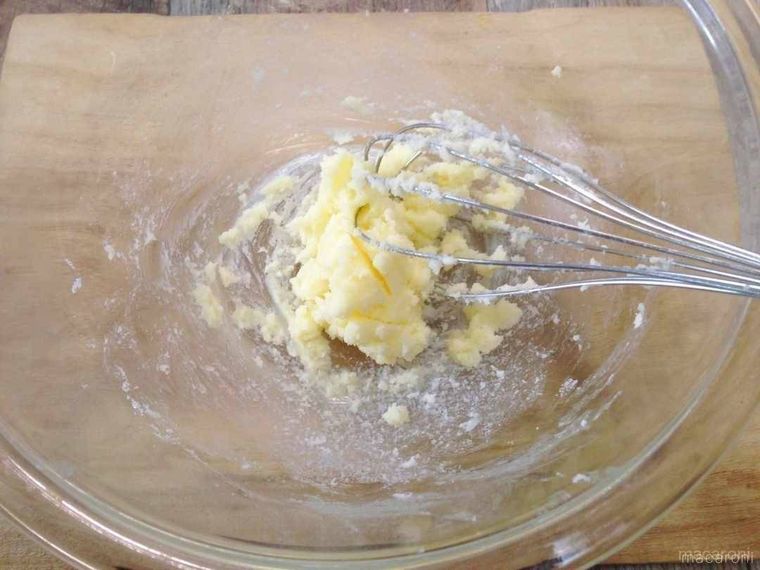 ホイッパーでボウルに入ったバターに砂糖を加えて混ぜる様子
