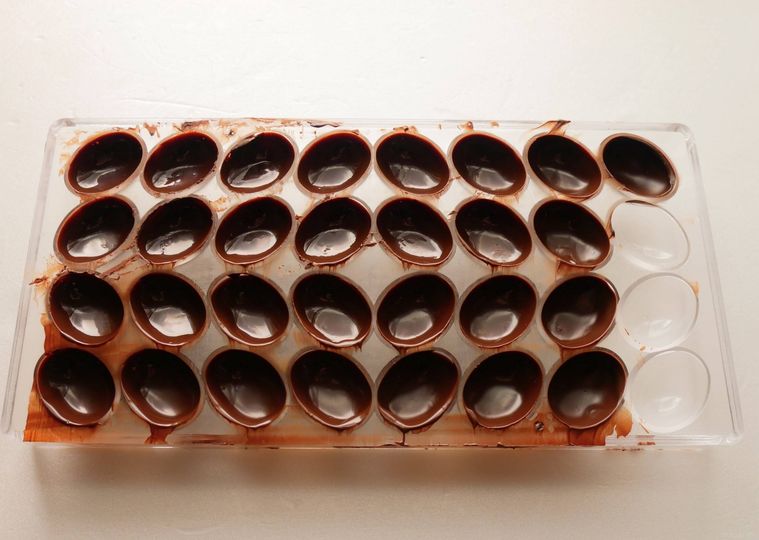 白いテーブルの上に置いた、チョコレートを流した型