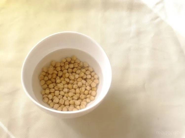 白いカップに入った、水につかったひよこ豆