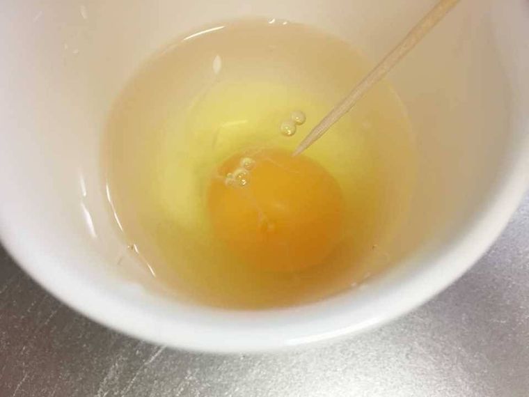 卵に爪楊枝で穴を開ける様子