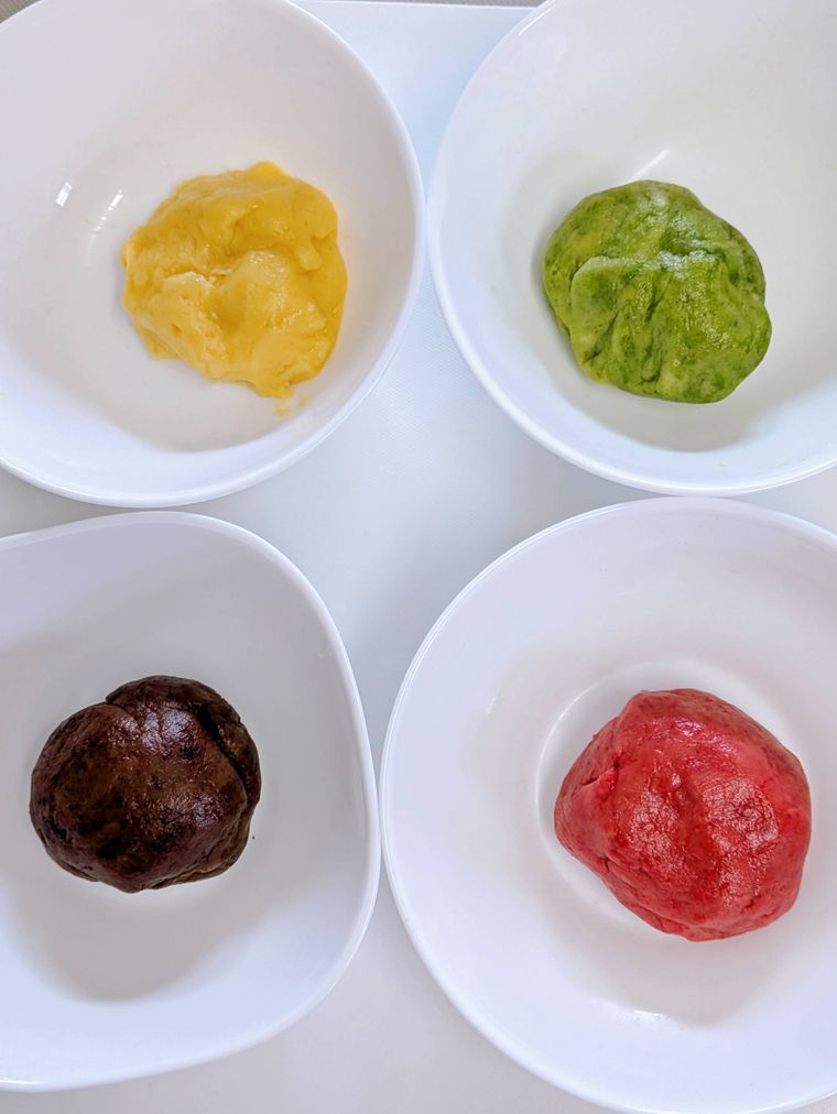 白いボウルに入った4色のクッキー生地
