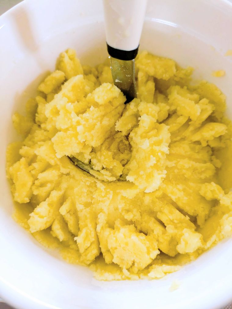 耐熱ボウルの中に入ったじゃが芋とマッシャー