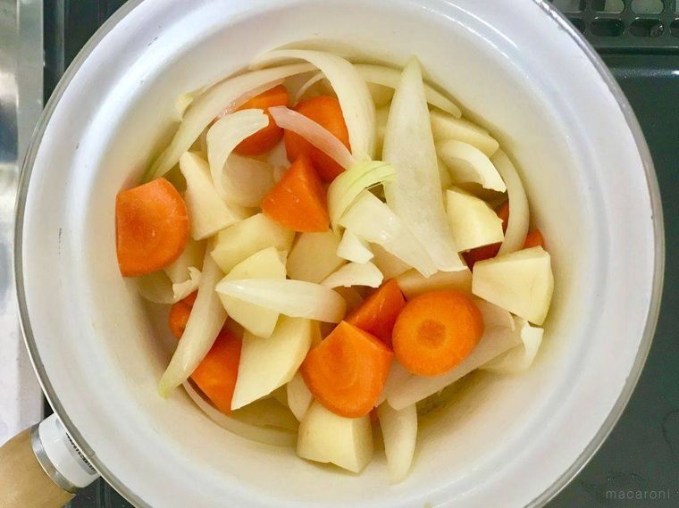 白い鍋で炒めているにんじん、じゃがいも、玉ねぎ